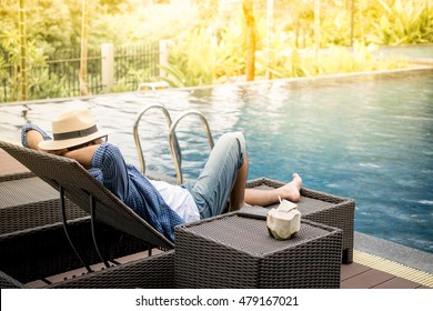 Relax In The Pool. Young And Successful Man Lying On A Sun Lounger At The Hotel On The Background Of Sunset.