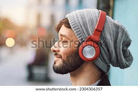 Relax, smile and man with headphones for music, radio or a podcast in the city. Happy, freedom and a young person sitting, enjoying and listening to audio, calm songs or zen sound while downtown