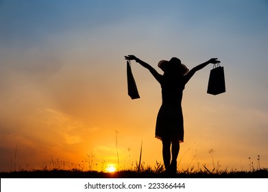 Relax Woman Holding Shopping Bags In Sunset Silhouette