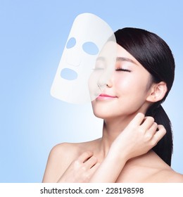 Relax Young Woman With Cloth Facial Mask Isolated On Blue Background, Concept For Skin Care And Moisture, Asian Beauty