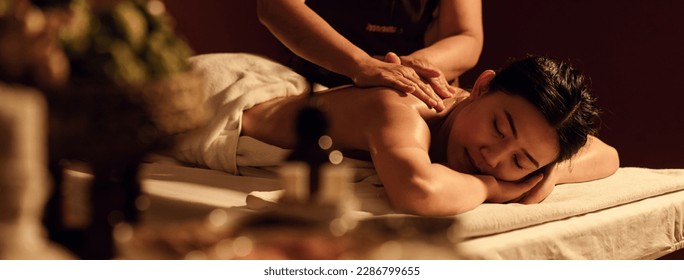 Relaxation Asian woman back massage with masseur in cosmetology spa centre. Relaxing female customer get service aromatherapy massage with masseuse in spa salon.