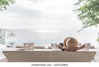 Relaxation holiday vacation of businessman take it easy happily resting on beach chair at swimming pool poolside beachfront resort hotel peacefully with sea or ocean view and summer sunny sky outdoor