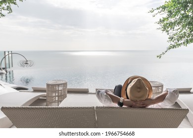 Relaxation holiday vacation of businessman take it easy for work-life balance resting happily on beach chair at swimming pool poolside beachfront resort hotel with summer sea sky ocean view background
