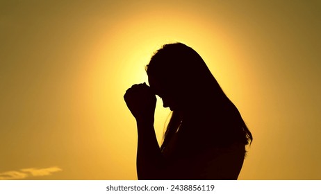 Relaxation and meditation in nature. Silhouette. Faith in god. Christian woman praying at sunset close-up. Girl on background of sky in rays of sun prayer to family and children. Apologize. Hope. Sky - Powered by Shutterstock