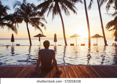 relaxation on the beach, young man enjoying beautiful sunset in luxury hotel near swimming pool