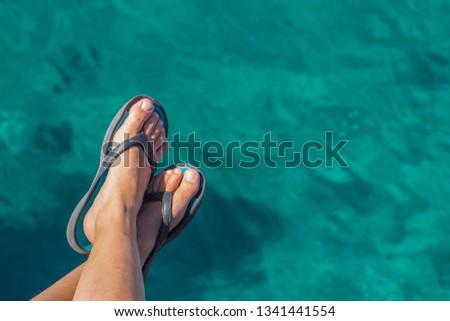 relaxation summer vacation concept simple wallpaper pattern with bare female feet in flip flops on vivid blue and green swimming pool water  background with empty copy space for your text