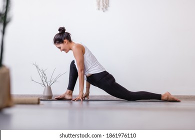 Relaxe Harmonious Beautiful Brunette Woman Yoga Instructor Standing In Anjaneyasana Pose, Horse Rider Exercise On Wooden Floor At Workout In White Yogi Classroom. Health And Spirit Improvement Concept