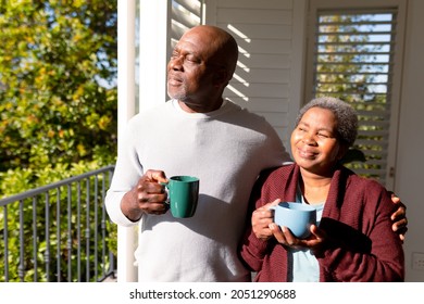 Relaxed african american senior couple drinking coffee standing on balcony in sun. retirement lifestyle, spending time at home and garden. - Powered by Shutterstock