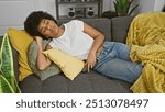 A relaxed african american woman napping on couch in cozy living room, with smartphone in hand.