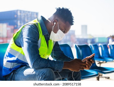 Relaxed African American worker man listening music podcast, Man wearing with disposable face mask sit at desk at container cargo site - Powered by Shutterstock