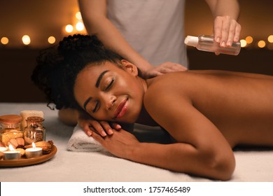 Relaxed African American Young Woman Enjoying Aromatherapy And Massage At Spa Lighted Up With Candles