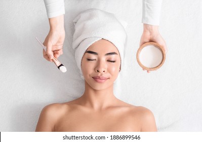 Relaxed Asian Woman Lying On Spa Table Ready For Facial Beauty Treatments, Attractive Korean Lady With Towel On Head Getting Wellness Procedures With Natural Cosmetics, Top View With Copy Space - Powered by Shutterstock