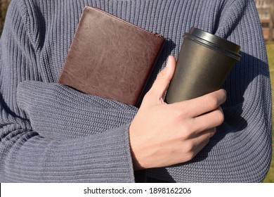 A Relaxed Attractive Handsome Young Man At His Terrace Reading An Old Book And Drinking Coffee