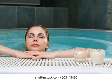 Relaxed beautiful young woman stay at the edge of a pool at spa club