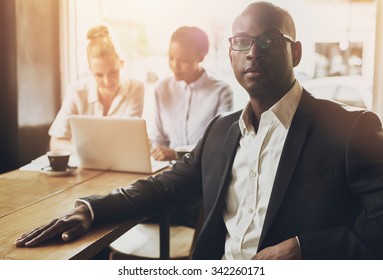 Relaxed Black Business Man At Office, People In Background