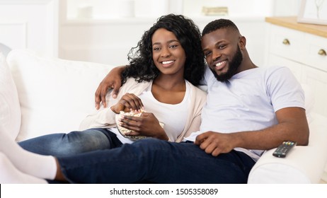 Relaxed Black Couple Watching Tv, Sitting On Couch With Popcorn At Home