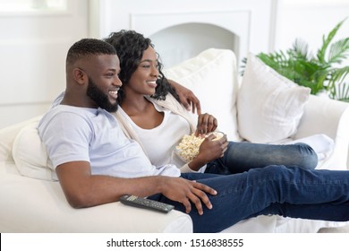 Relaxed Black Couple Watching Tv, Sitting On Couch With Popcorn At Home, Side View