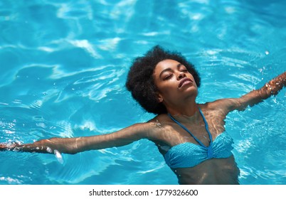 Relaxed Black Girl Floating In Transparent Water Of Swimming Pool Outside, Empty Space