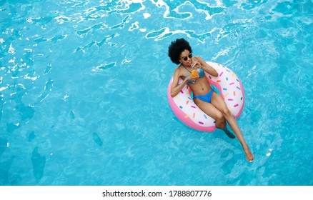 Relaxed Black Lady Floating On Inflatable Ring And Enjoying Her Cocktail Drink At Pool, Top View. Space For Text. Panorama