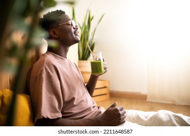 Relaxed black man drinking green smoothie at home. Side view of African American man enjoying healthy juice. - Powered by Shutterstock