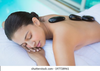 Relaxed brunette lying on towel having a hot stone massage outside at the spa - Powered by Shutterstock