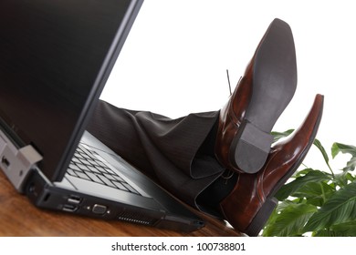 Relaxed businessman with his feet up on a desk next to laptop