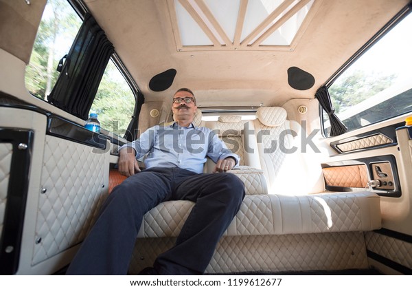 Relaxed businessman in\
moving car.  