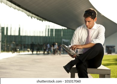 Relaxed businessman using his PC tablet while sitting on a bench - Powered by Shutterstock