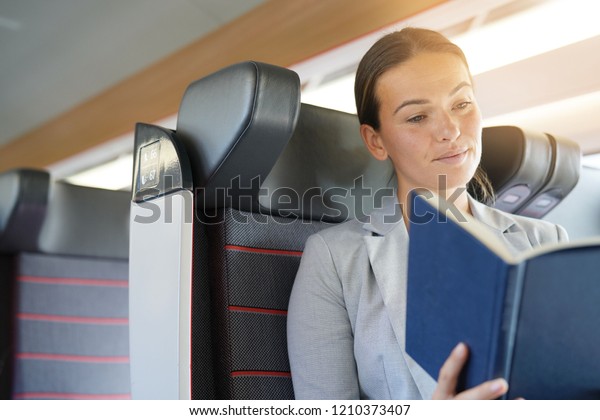 Relaxed businesswoman reading on a train                
             