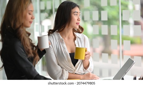 Relaxed Businesswomen Having A Coffee Together At Office Break Room  In The Morning.  