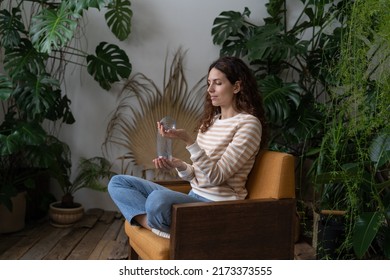 Relaxed Calm Woman Playing With Spring Toy For Stress Relief Sit Crossed Legs In Armchair. Female Relieve Stressful Tension With Stretchable Spring Has Break From Work At Home Office In Indoor Garden