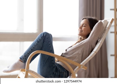 Relaxed Calm Young Woman Lounging Sitting In Comfortable Wooden Rocking Chair Breathing Fresh Air Dreaming, Happy Lazy Girl Chilling Relaxing Enjoying No Stress Free Peaceful Quiet Weekend At Home