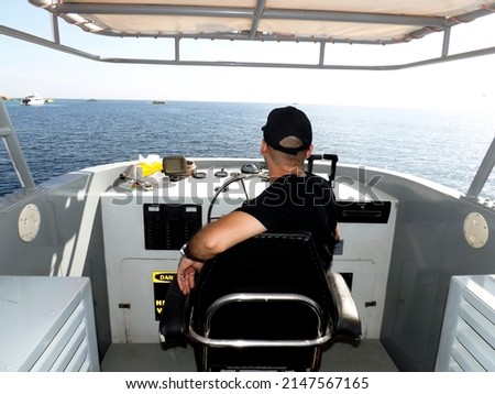 A relaxed captain on a steering wheel and navigating sail boat or yacht floating in the red sea, selective focus an unrecognized person yachting a ship in the middle of the sea in the daylight