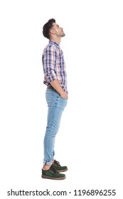 relaxed casual man waiting in line looks up at something while standing on white background with hands in pocets, full length picture
