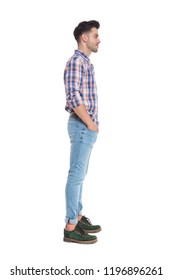 relaxed casual man wearing a plaid shirt waiting in line while standing on white background with hands in pockets, full length picture
