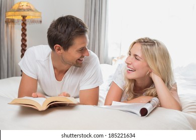 Relaxed Casual Young Couple Reading Books In Bed At Home