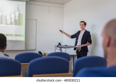 Relaxed Confident Smart Student Presenting His Study Work In Front Of Whiteboard, Defending His Thesis. Doctoral Thesis Defense On Faculty.