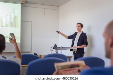 Relaxed Confident Smart Student Presenting His Study Work In Front Of Whiteboard, Defending His Thesis. Doctoral Thesis Defense On Faculty.