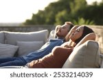 Relaxed couple resting sitting in an exterior sofa in a terrace