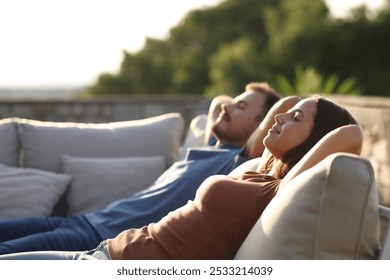 Relaxed couple resting sitting in an exterior sofa in a terrace - Powered by Shutterstock