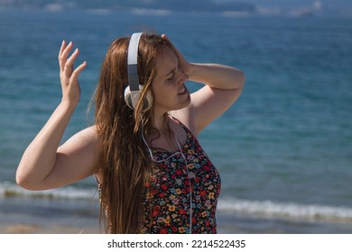 Relaxed Curvy Woman With Headphones Dancing On The Beach