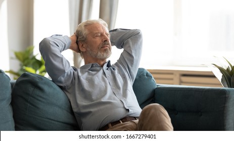 Relaxed Elderly 60s Husband Rest On Comfortable Couch In Living Room Hands Overhead Eyes Closed, Peaceful Mature 50s Man Relax On Cozy Sofa At Home Take Nap Daydream On Weekend, Stress Free Concept