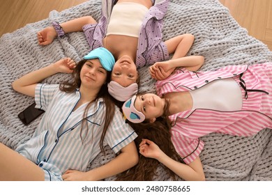 Relaxed family time with playful smiles and cozy blankets. Pajama Party. Girls' night out. Portrait three sisters - Powered by Shutterstock