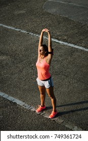 Relaxed Female Runner Doing Stretching And Breathing Exercise For Cooling Down After Running And Working Out.