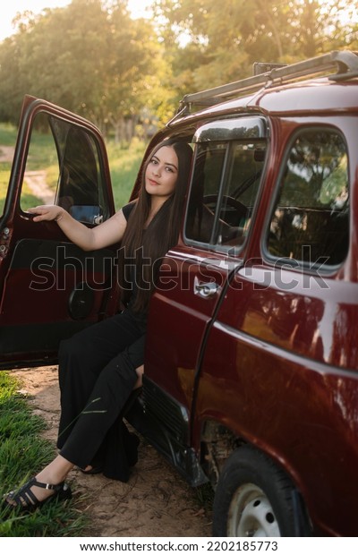 Relaxed girl on a car in the middle of nature\
and a beautiful\
landscape
