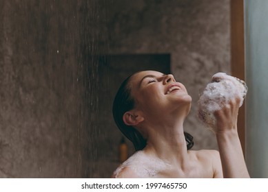 Relaxed Half Naked Topless Young Woman 20s Taking Hot Shower Use Blue Washcloth With Closed Eyes In Bathroom Do Morning Routine In Brown Background. Skin Care Healthcare Cosmetic Procedures Concept.