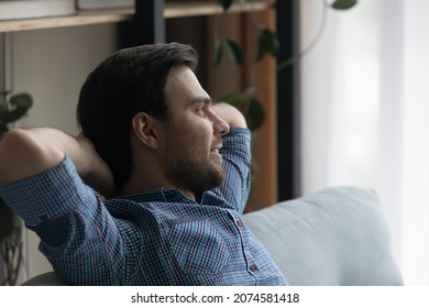 Relaxed Happy Carefree Millennial Generation Man Sitting On Cozy Couch, Breathing Fresh Air Looking In Distance Daydreaming Meditating, Visualizing Future Or Planning Weekend, Enjoying Peaceful Time.