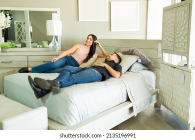 Relaxed Happy Couple Smiling While Trying On A New Mattress And Furniture Bedroom While Shopping