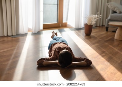 Relaxed happy young indian ethnicity woman homeowner lying alone on warm wooden floor with underfloor heating, enjoying carefree peaceful weekend leisure time alone in modern stylish living room. - Shutterstock ID 2082214783