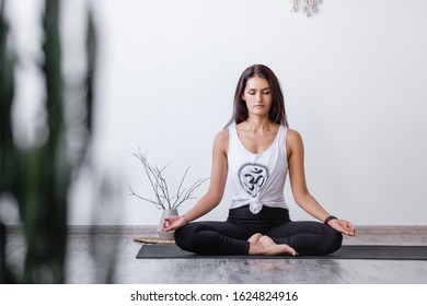 Relaxed Harmonious Beautiful Brunette Woman Yoga Instructor Doing Lotus Position. Closed Eyes, Mudra Gesture, Sitting On Rug On Floor During Workout. Health And Spirit Improvement Concept. Copyspace